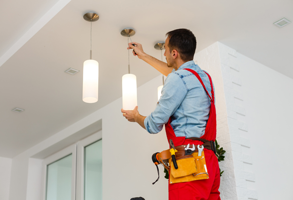 An electrician following the regulations whilst installing ceiling lights.